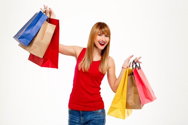 Belle jeune femme debout avec achats sur mur blanc