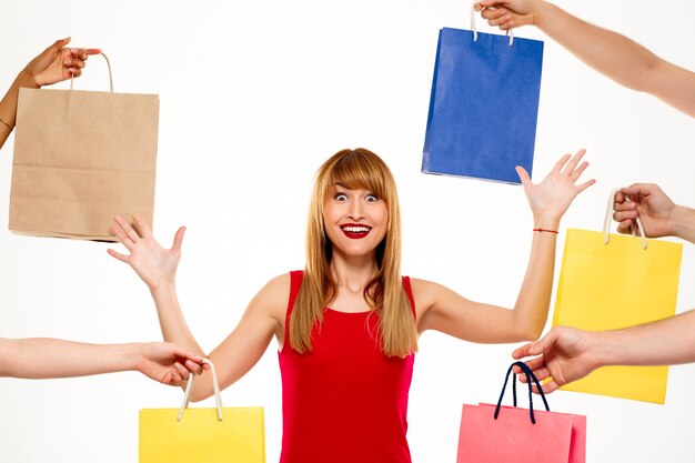 Belle jeune femme debout parmi les achats sur mur blanc