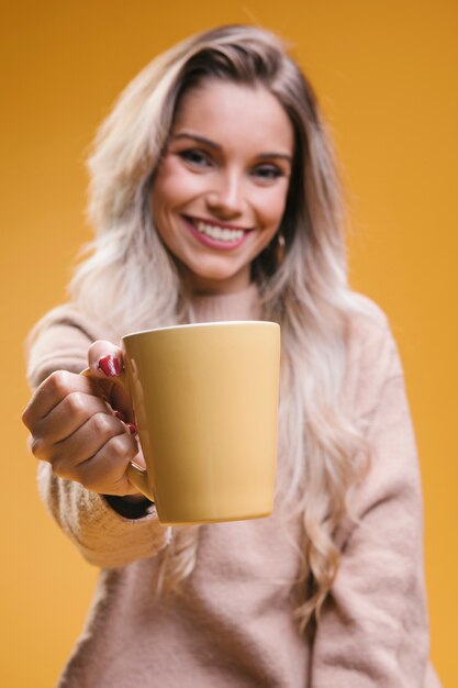 Belle jeune femme donnant une tasse de café et regardant la caméra