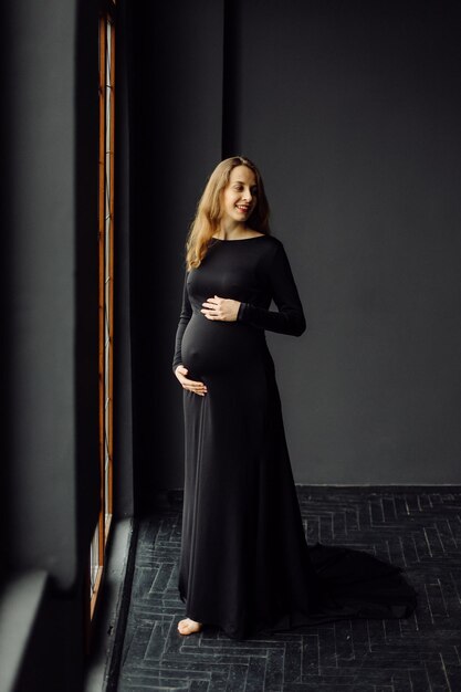 Belle jeune femme enceinte en robe noire Concept de look de mode de grossesse