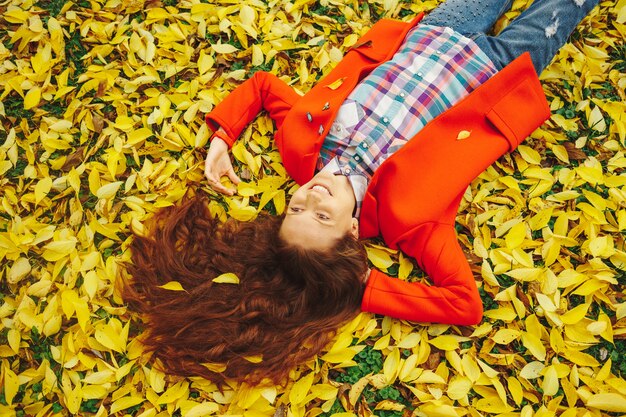 Belle jeune femme entourée de feuilles d'automne