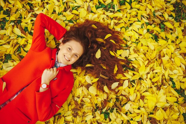 Belle jeune femme entourée de feuilles d'automne
