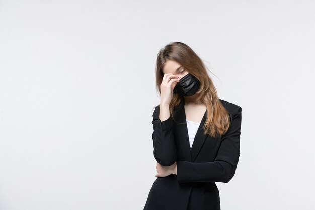 Belle jeune femme épuisée en costume portant un masque chirurgical sur blanc