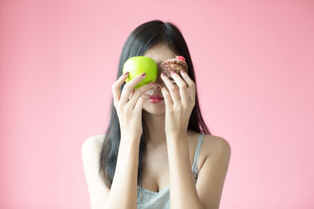 Belle jeune femme faisant un choix entre un gâteau et une pomme