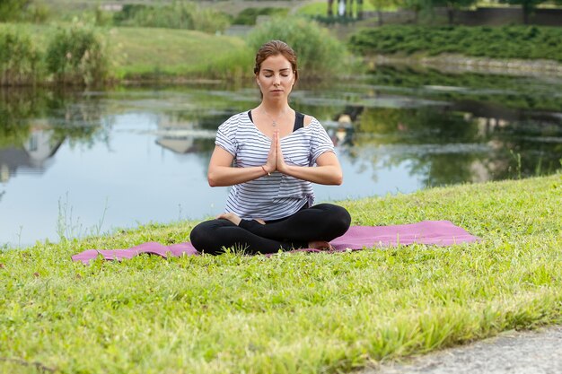 Belle jeune femme faisant des exercices d'yoga dans le parc verdoyant. Concept de mode de vie et de remise en forme sain.