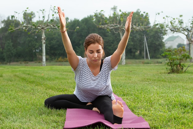 Belle jeune femme faisant des exercices d'yoga dans le parc verdoyant