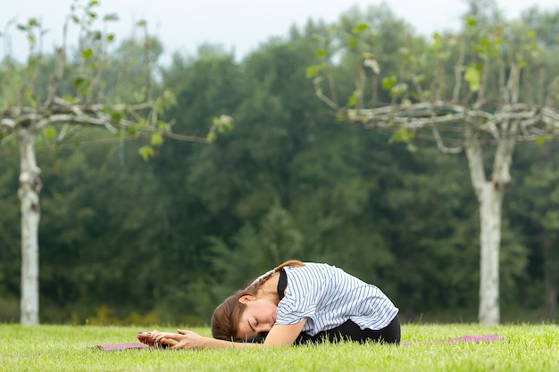 Belle jeune femme faisant des exercices d'yoga en plein air