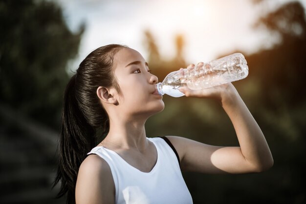 Belle jeune femme fitness boire de l&#39;eau après l&#39;exercice en cours d&#39;exécution