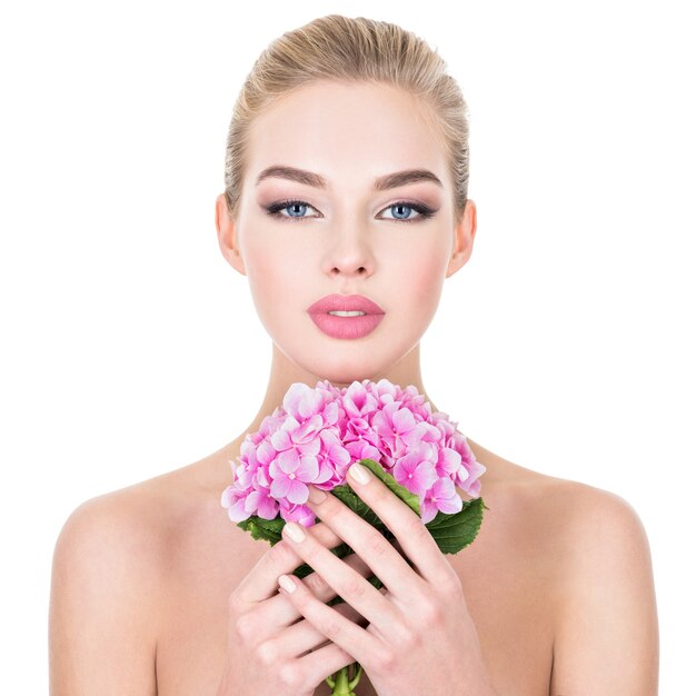 Belle jeune femme avec des fleurs près du visage.