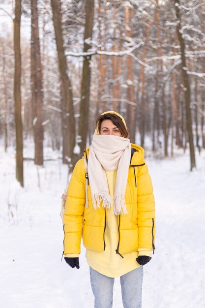 Belle jeune femme gaie dans une forêt d'hiver paysage enneigé s'amusant se réjouit en hiver et la neige dans des vêtements chauds