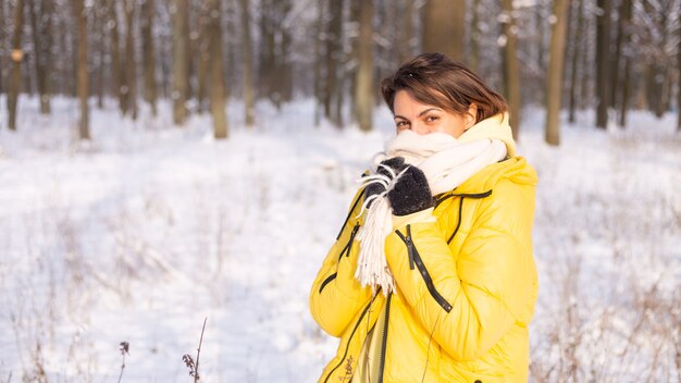Belle jeune femme gaie dans une forêt d'hiver paysage enneigé s'amusant se réjouit en hiver et la neige dans des vêtements chauds