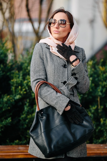 Belle jeune femme heureuse dans un manteau posant dans le parc