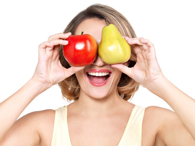 Belle jeune femme heureuse tient la pomme et la poire isolé sur blanc.