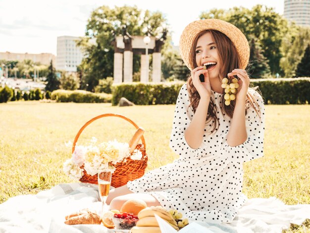 Belle jeune femme hipster en jeans d'été à la mode, T-shirt rose et chapeau. Femme insouciante faisant un pique-nique à l'extérieur.