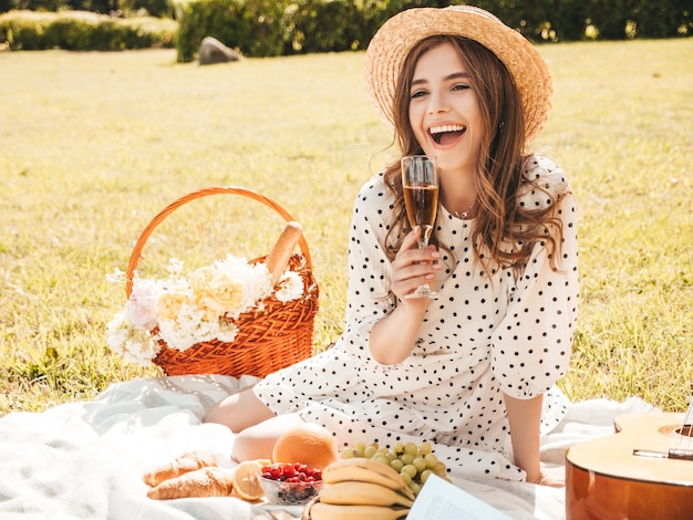 Belle jeune femme hipster en robe d'été à la mode et chapeau. Femme insouciante faisant un pique-nique à l'extérieur.