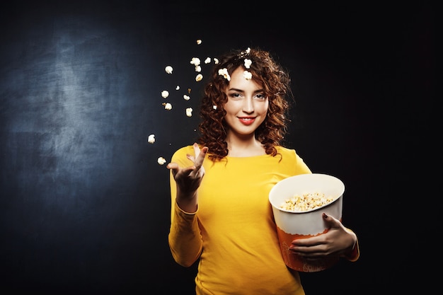 Belle jeune femme jetant du pop-corn en l'air en souriant