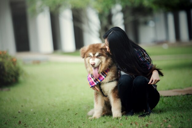 Belle jeune femme jouant avec son petit chien dans un parc en plein air. Portrait de mode de vie.