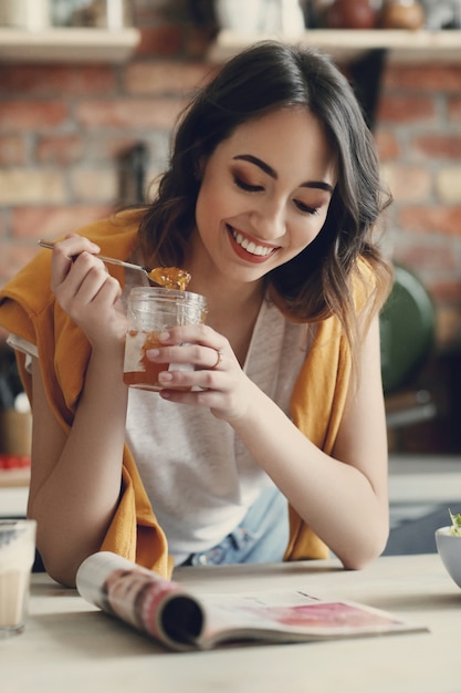 Belle jeune femme lisant un magazine à la maison