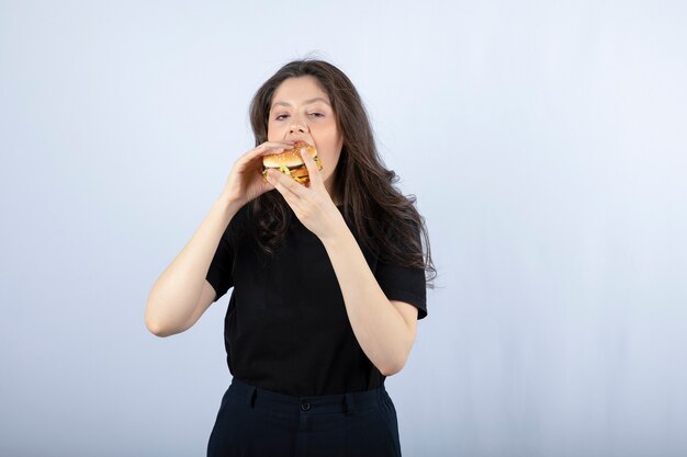 Belle jeune femme mangeant un délicieux hamburger de boeuf.