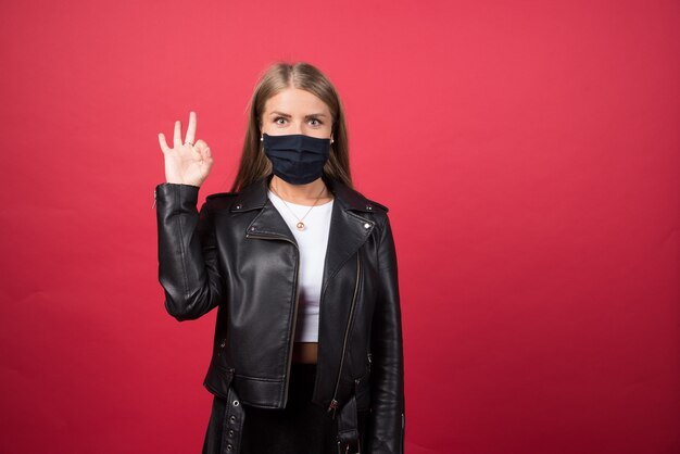 Belle jeune femme avec un masque médical montrant un geste correct