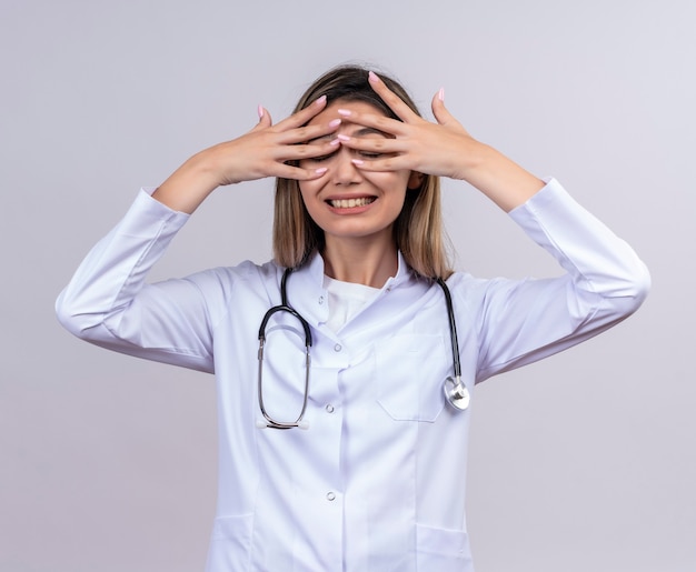 Belle Jeune Femme Médecin Portant Blouse Blanche Avec Stéthoscope Couvrant Les Yeux Heureux Et Positifs Avec Les Doigts Souriant En Attente De Surprise