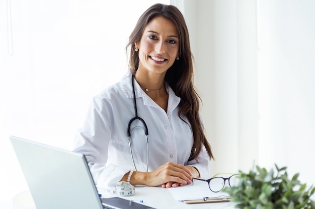 Belle jeune femme médecin regardant la caméra dans le bureau.