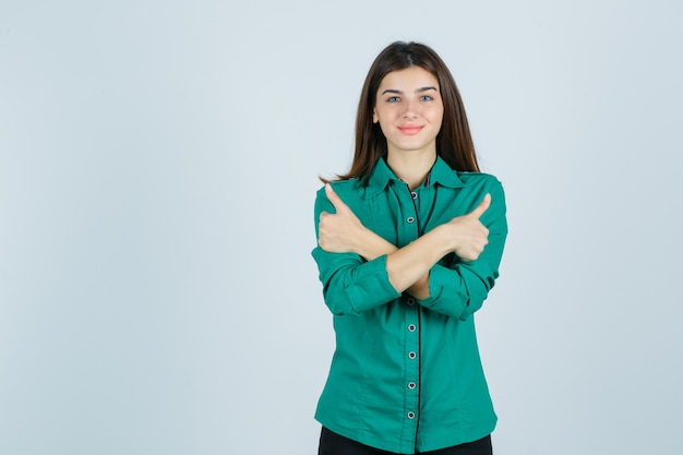 Belle jeune femme montrant deux pouces vers le haut en chemise verte et à la joyeuse vue de face.