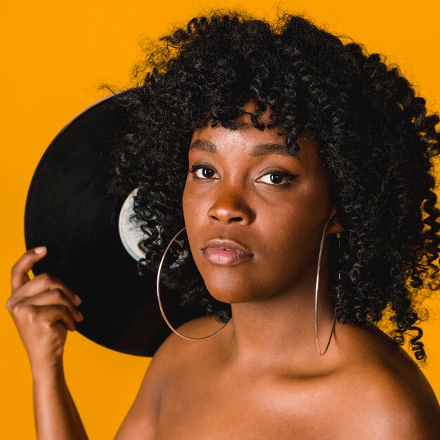 Belle jeune femme noire avec plaque de musique sur fond coloré