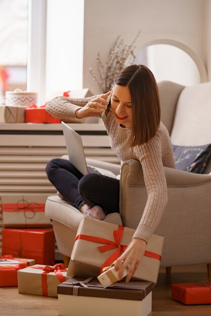 Belle jeune femme avec ordinateur portable, parler au téléphone mobile alors qu'il était assis dans un fauteuil confortable