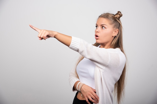 Photo gratuite belle jeune femme pointant avec la main et le doigt sur le côté.