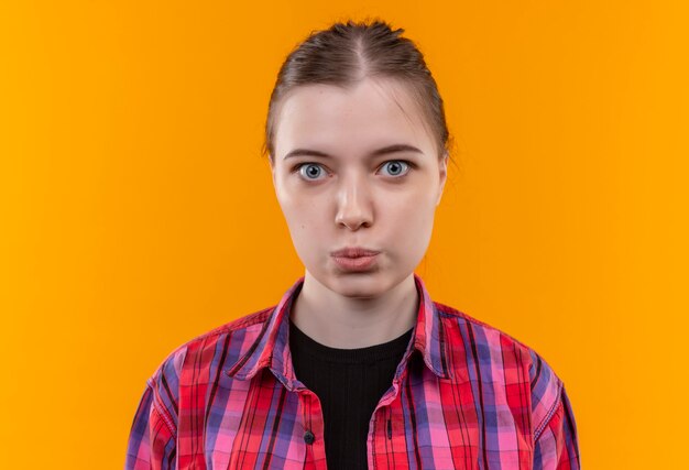 Belle jeune femme portant une chemise rouge montrant le geste de baiser sur un mur jaune isolé