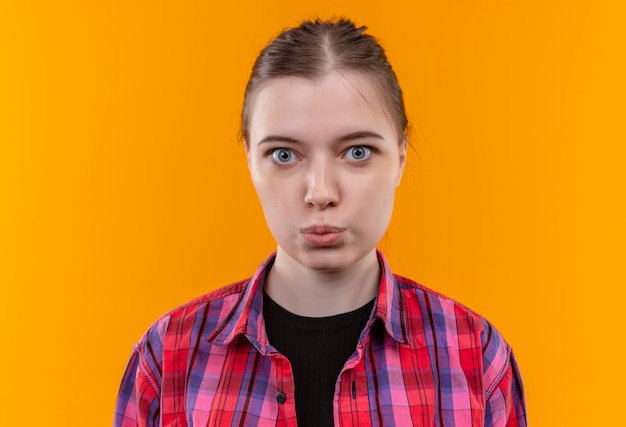 Belle jeune femme portant une chemise rouge montrant le geste de baiser sur un mur jaune isolé