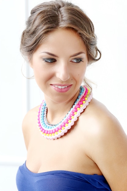 Belle jeune femme portant un collier coloré et souriant