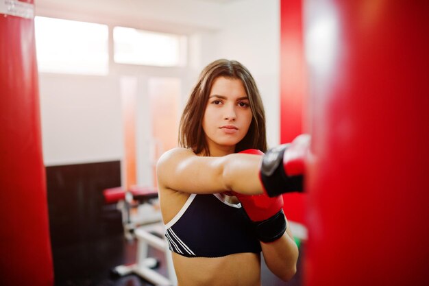 Belle jeune femme portant des gants de boxe faisant des exercices et travaillant dur dans la salle de gym et profitant de son processus d'entraînement