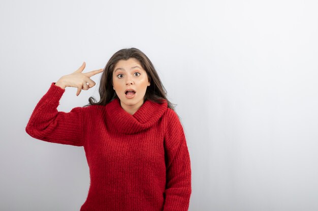 Belle jeune femme portant un pull décontracté et pointant vers la tête avec un doigt.