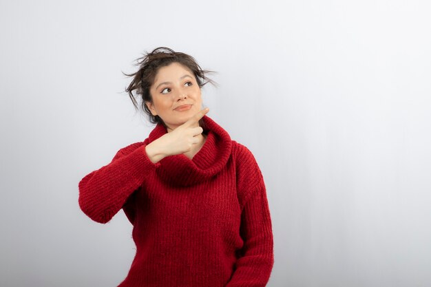 Belle jeune femme portant un pull et pointant le doigt sur le côté.