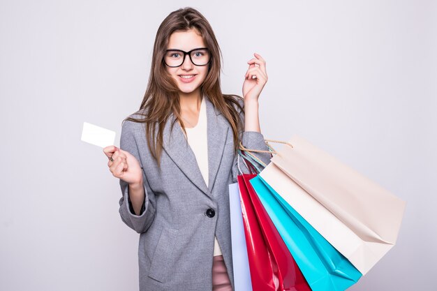 Belle jeune femme portant des sacs à provisions avec carte de crédit isolé sur fond blanc