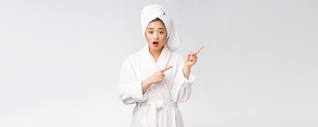 Belle jeune femme portant une serviette de douche après le bain sur fond blanc isolé pointant du doigt