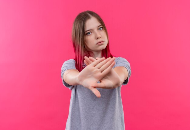 Belle jeune femme portant un t-shirt gris montrant le geste d'arrêt sur un mur rose isolé