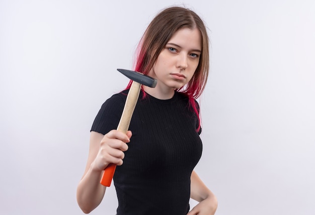 Belle jeune femme portant un t-shirt noir tenant un marteau sur un mur blanc isolé