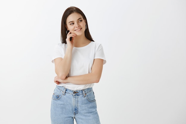 Belle jeune femme posant contre le mur blanc