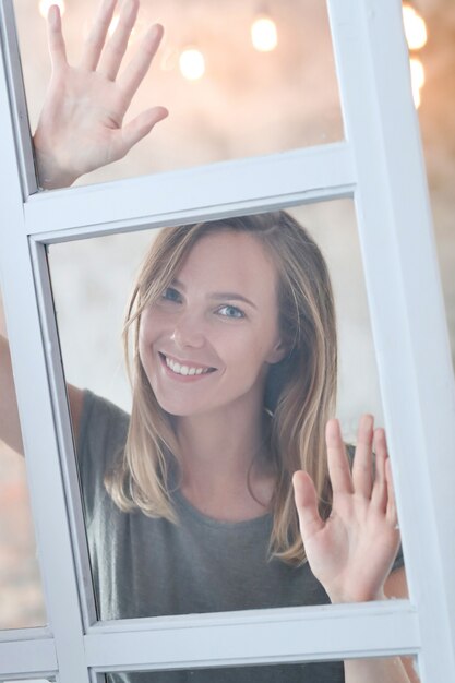 Belle jeune femme posant derrière la fenêtre