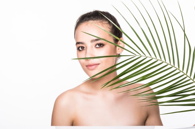 Belle jeune femme posant avec une feuille de palmier verte