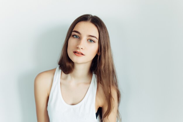 Belle jeune femme posant sur un mur blanc