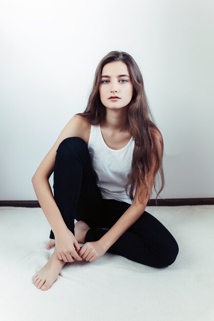 Belle jeune femme posant sur un mur blanc