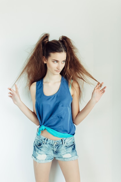 Belle jeune femme posant sur un mur blanc