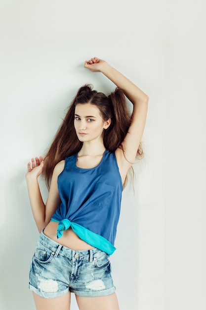 Belle jeune femme posant sur un mur blanc