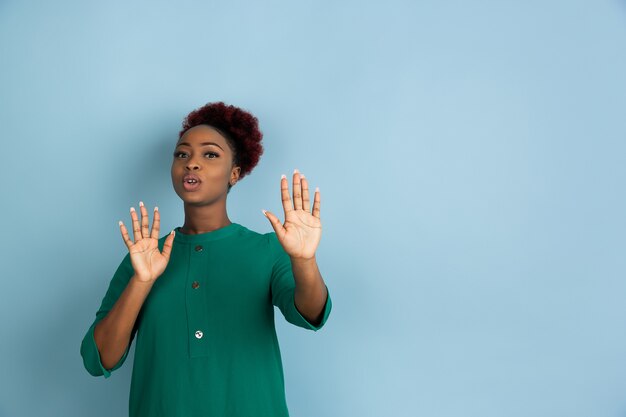 Belle jeune femme posant sur le mur bleu