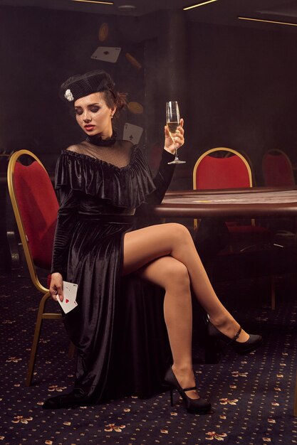 Belle jeune femme pose contre une table de poker dans un casino de luxe.