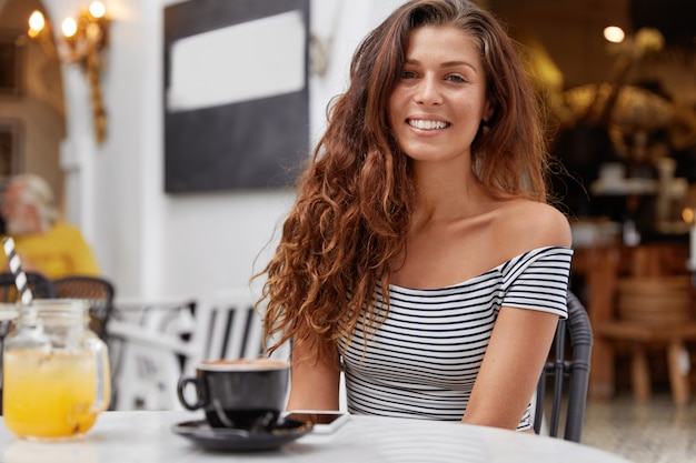 Belle jeune femme positive se sent heureuse dans un café
